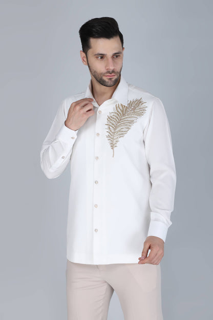 Man wearing a white shirt with gold embroidery on a gray background