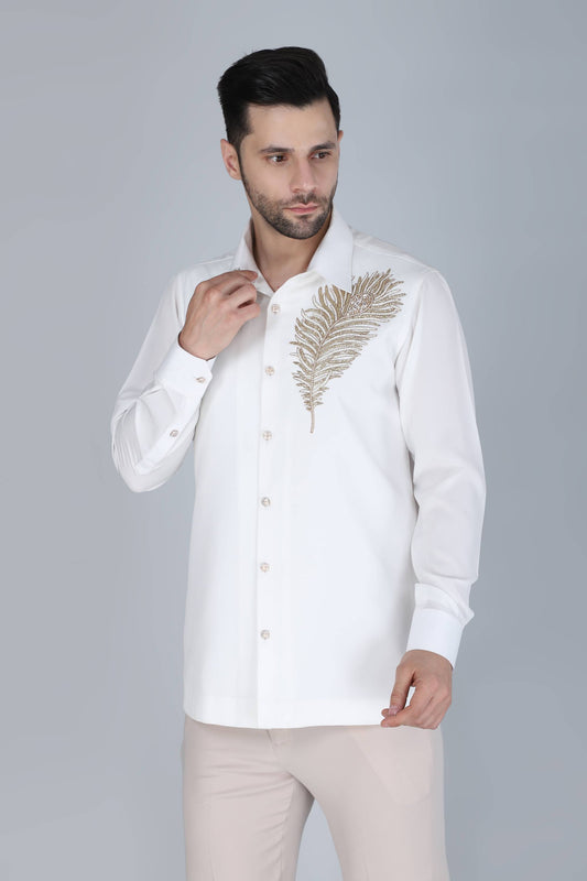 Man wearing a white shirt with gold embroidery on a gray background